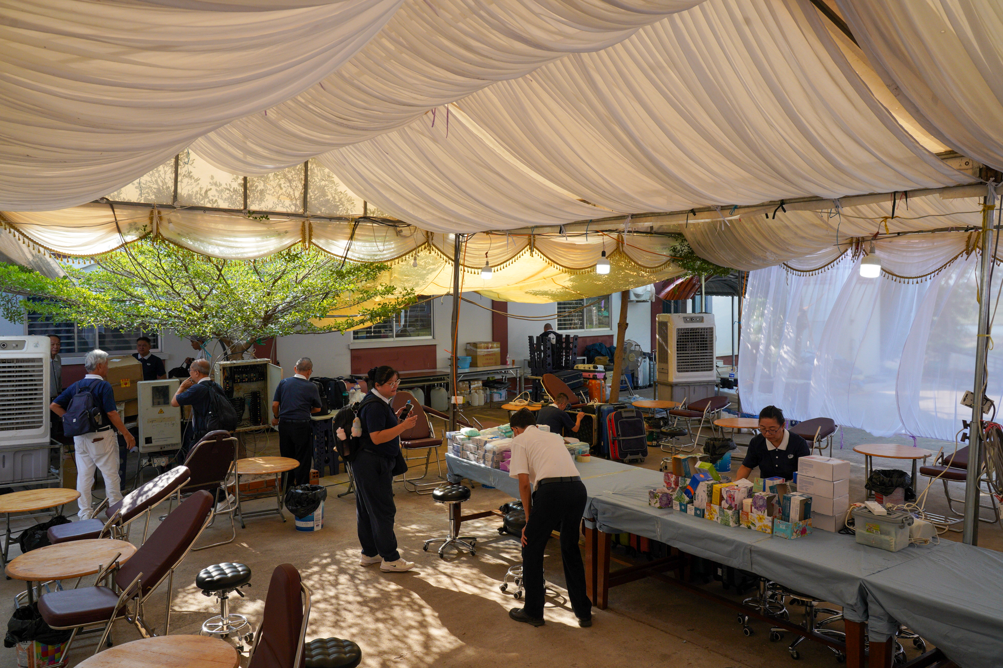 搭帐篷、摆放器材、就医椅和冷风机，为村民提供干净整齐的就医环境。摄/ 林春慧